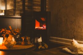 a cat sitting on a table in front of a fireplace